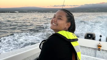 Bree on a boat, with Hilo Bay and island in background.